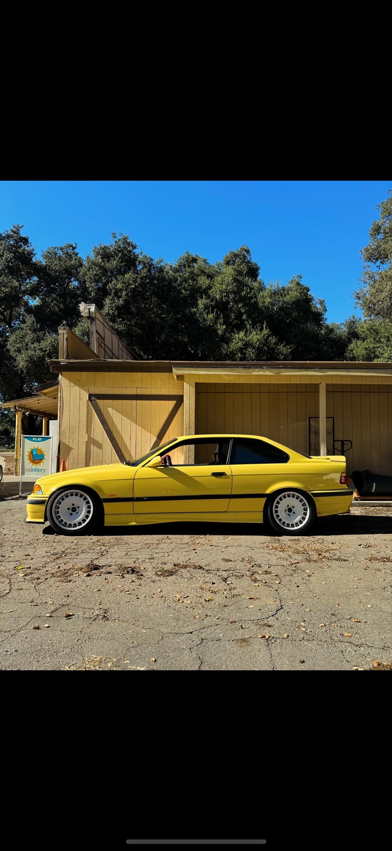 Built E36 BMW with white wheels, side profile in golden California light